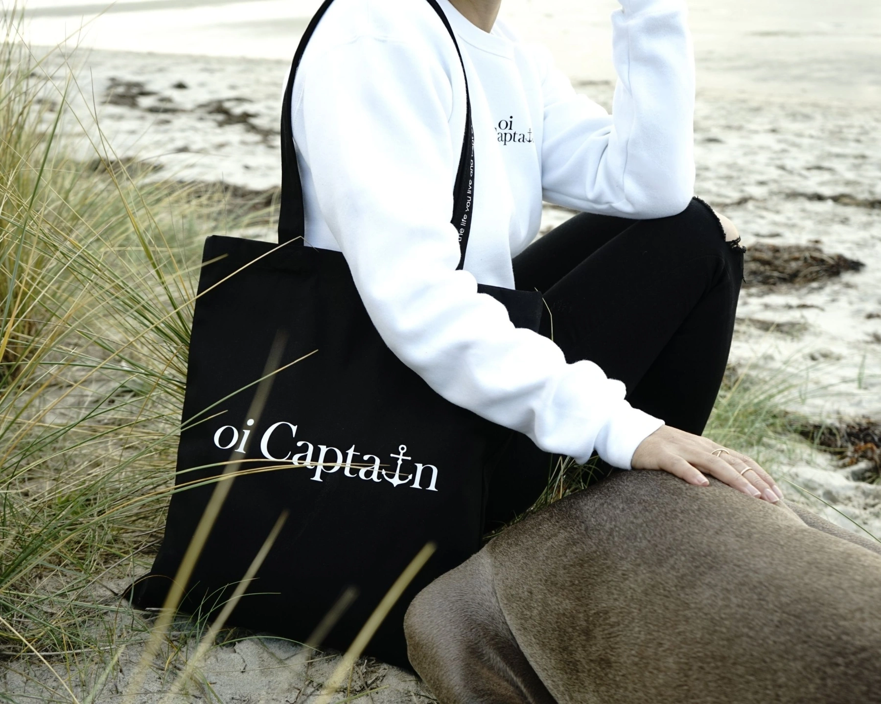 female model featuring oi captain vagabond tote bag black with harvey the weimaraner coastal lifestyle.jpg