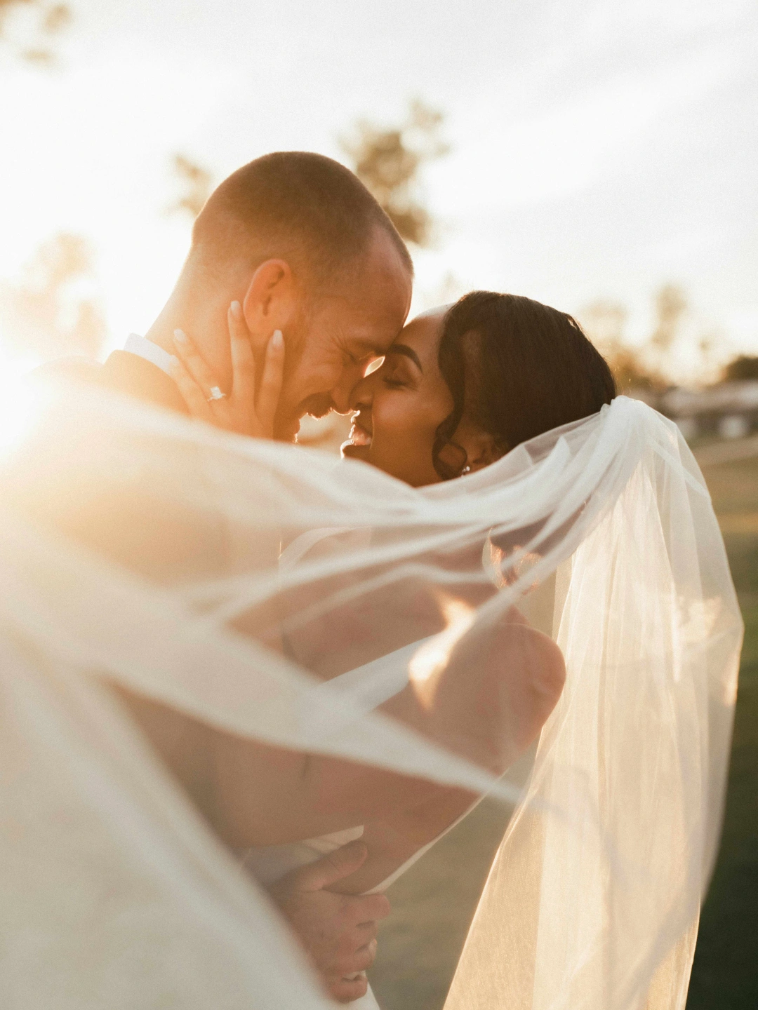 bride-and-groom-embrace-smiling-at-sunset.jpg