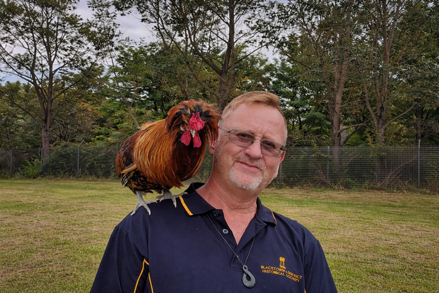 Man with rooster in sunny field.png