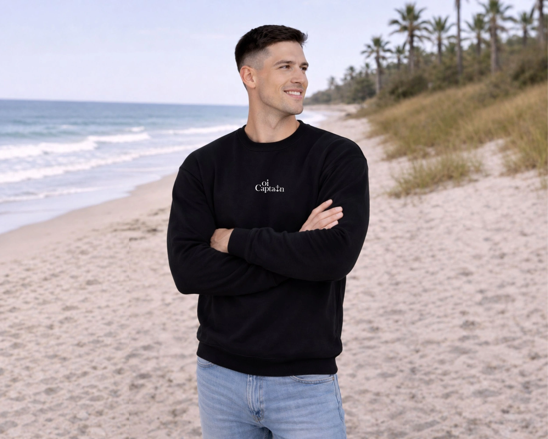 male model wearing black Oi Captain Dolce Vita Crew Neck Sweatshirt front view on a beach with palm trees in the background.jpg