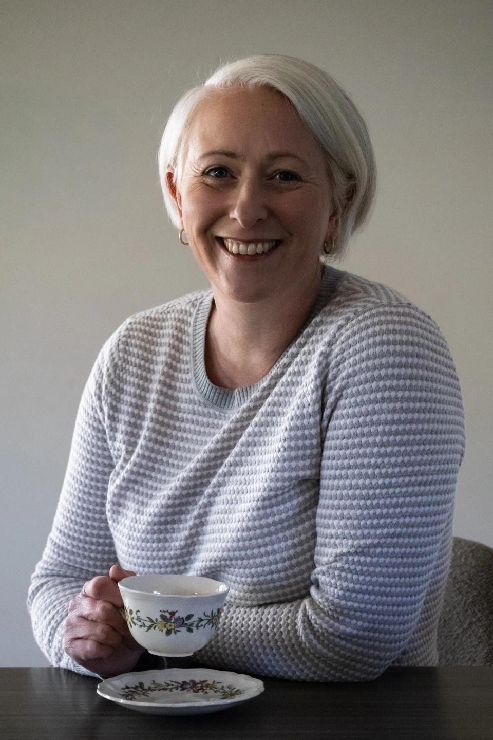 Casual photo of Frances Orr stripy jumper, silver grey hair, vintage cup and saucer