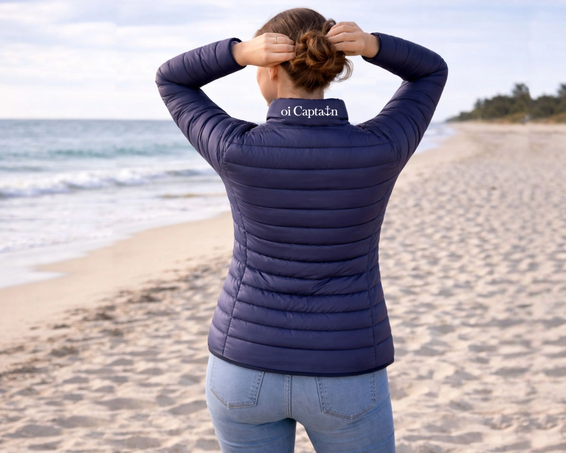 female model wearing oi captain venus puffer jacket navy back view coastal lifestyle.jpg